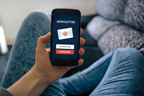 Man holding a mobile device with a newsletter signup